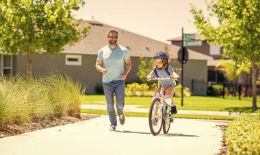Baba oğul birlikte dolambaçlı yollarda yol alırlar. Baba-oğul gezintisi. Baba ve oğul babalığında. Baba ve oğlunun babalığı güneşli parkta bisiklet sürüyor. Bisiklet ikilisi.