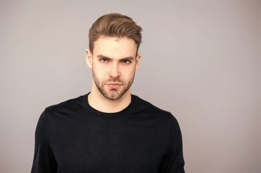 Beyazlı genç bir adam gri yolda izole edilmiş. Kendine güvenen adam portresi. Erkeklerin cilt bakımı. Erkek derisi. Adamın şık bir saç kesimi var. Moda saç stili olan bir adam. Sıradan erkek tarzı. Boşluğu kopyala.