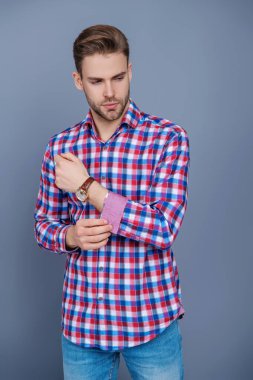 Sıradan bir tişörtle genç bir adamın portresi. Tıraşsız adamın şık bir portresi. Gri yolda izole edilmiş bir adam. Kareli gömlek giyen milenyum adamı. Milenyum erkeğinin gündelik tarzı. Gitmeye hazırlanıyorum..