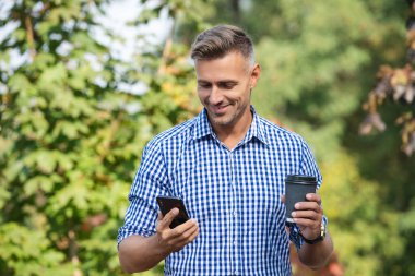 Modern mobil iş iletişimi. İş adamı telefonda mesajlaşıyor. Telefonla konuşan bir adam. Telefon kullanımı. Dışarıdaki telefonda mesajlaşan bir adam. Kahve molasında iş mesajlaşması. Haberler iyi..