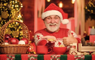 New year. Cozy home. Christmas eve treats. Senior man Santa claus drinking tea. Christmas cocoa recipe. Winter holiday. Grandpa with mug. Cozy interior. Hot beverage and cookies. Cozy atmosphere. clipart