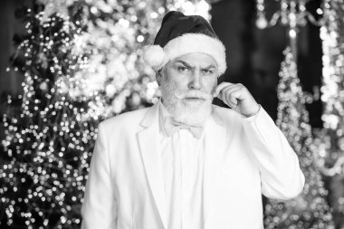 Bekliyorum. Gerçekten olgun bir adam, beyaz takım elbise. Smokin işinde başarılı bir iş adamı. Son sınıf Noel Baba ışıklandırması aydınlatılmış arka plan. Parlak ve neşeli Noel havası. Yeni yıl partisi.