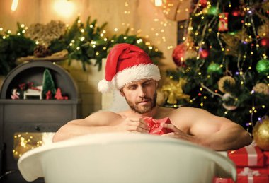 Kendimi şımartıyorum. Tatiller rahatlatır. Noel turu konsepti. Küvette yatan adam hediye kutusuyla rahatlar. Seksi maço, küvette rahatlıyor. Spa ve sağlık. Yeni yıl kutlamalarının tadını çıkar. Kitap otelde kalır..