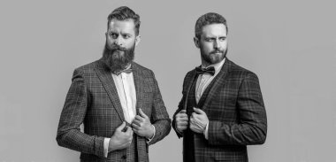 Resmi smokin giymiş, beyaz, zarif erkekler. Smokinli adamlar gri arka planda izole edilmiş. Smokinli iki adam. Stüdyoda smokin giyen adamların fotoğrafı..