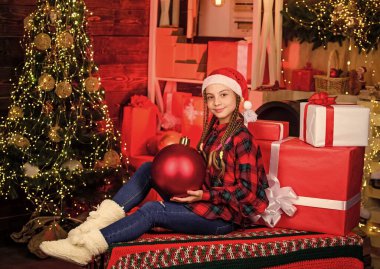 Mutlu yıllar. Kırmızı Noel Baba şapkalı çocuk. Elinde hediye kutusu olan çocuk. Kış alışverişi. Sihirli hediye kutusu. Noel hediyesi kutusu olan mutlu küçük bir kız. Xmas havası. Aile tatili. Alışveriş merkezindeki çocuk.