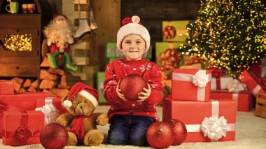 Mutlu çocuk Noel Baba şapkası. Oğlum kış tatilini kutlamaya hazır. Küçük çocuk heyecanla hediye bekliyor. Çocuk dekoratif balo düzenliyor. Noel için oyuncak hediye getirdim. Mutlu noeller. Mutlu yıllar..