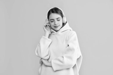 Neşeli genç kadın sarı arka planda kulaklıkla müzik dinliyor..