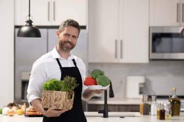 Akşam yemeği için sağlıklı yemek. İspanyol adam mutfakta yemek hazırlıyor. Aşçı adam evde sağlıklı yemek pişiriyor. Mutfaktaki adam. Sağlıklı beslenme, vejetaryen. Boşluk afişini kopyala.