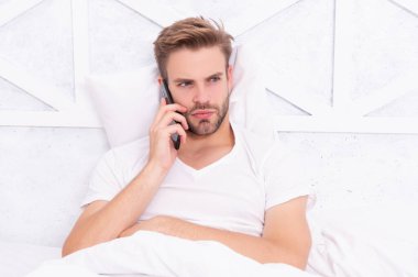 Hastalık izni iste. Milenyum adamı yatak odasında akıllı telefon kullanır. Yatakta telefonla konuşan genç bir adam. Telefon var. Yatakta akıllı telefonu olan bir adam. Akıllı telefon iletişimi. Hasta adam arıyor..