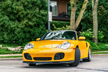 Chicago, Illinois - 29 Eylül 2024: Porsche 911 Turbo Carrera S sarı renk. Porsche 911 turbo Carrera S yolda. ön görünüm