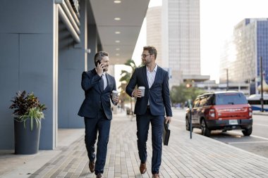 Şehirde yürüyen ve konuşan iki CEO iş adamı. İş adamları konuşuyor. Yürüyen ve konuşan iki iş adamı. New York 'ta iş arkadaşı yürüyüşü. Başarı. Takım elbiseli işadamları dışarıda yürüyor..