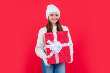 Noel tatili. Stüdyoda Noel hediyeli mutlu genç kız. Genç kız Noel hediyesini kırmızı arka planda izole etmiş..