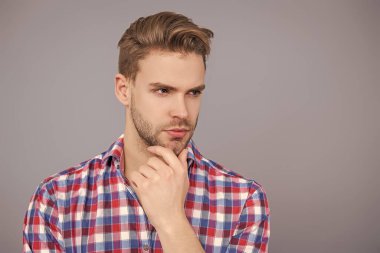 Yakışıklı genç adam. Sıradan gömlekli bir adamın portresi. Gri üzerinde kollarını çapraz tutuyor. Tıraşsız erkek derisi. Erkek güzelliği ve saç stili. Gündelik giyinen milenyum adamı. Seksi portre..