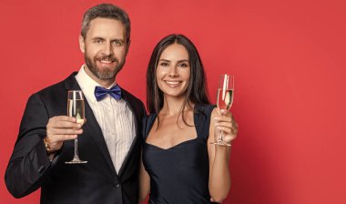 Resmi olarak bir çift. Romantik randevu kutlamaları. Sevgililer Günü. Yıldönümünü kutlayalım. Aşık çift nişanı kutluyor. Zarif çift kırmızı pankartta izole edilmiş şampanya içiyor..