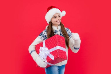 Noel tatili. Stüdyoda noel hediyesiyle gülümseyen genç kız. Genç kız Noel Baba 'yı kırmızı arka planda izole bir şekilde bekletiyor..