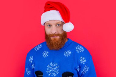 Noel tatili. Noel tatilinde Noel Baba şapkalı beyaz adam yüzü kırmızı arka planda izole edilmiş. Yılbaşı partisindeki adam..