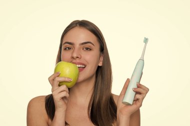 Dişlerini fırçalayan bir kız. Beyaz dişler. Diş sağlığı kliniği. Elektrikli diş fırçası. Beyaz tenli dişlek kadın gülüşü. Dişlerini elektrikli diş fırçasıyla fırçalayan bir kadın. Yumuşak diş fırçalama.