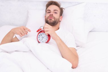 Erken kalkmak. Uyanma ve kalkma vakti geldi. Sabah uyanması. Yatakta yatarken elinde çalar saatle uyuyan adam. Sabah uyanışı. Uykulu adam çalar saati kapatıyor. Uyku eksikliği..
