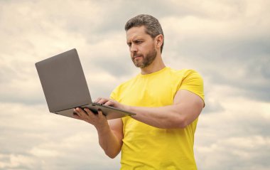 busy man working online on laptop on sky background.