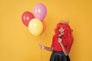 Sarı arka planda mikrofon ve parti balonu olan tacın içindeki mutlu çocuk..