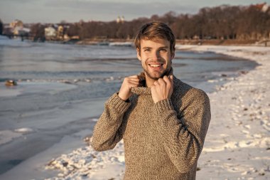 Açık havada süveter giyen mutlu stil sahibi bir adam. Tatillerde kazaklı bir adam. Adam kışlık kazak giyiyor. Kışın açık havada kazak giyen adam..