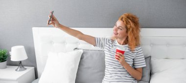 Kadın blogcu gülümsemesi kahveyle telefonda selfie yapıyor. Selfie zamanı. Kadının telefonuna görüntülü arama geldi. telefon özçekimi ve kadın videosu.