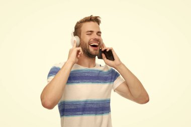 Beyazda izole edilmiş kablosuz kulaklıklı modern telefon. Milenyum adamı kulaklıkla müzik dinliyor. Telefon kullanan kulaklıklı bir adam. Gen z adam eğitim ya da müzik için telefon uygulaması kullanın.