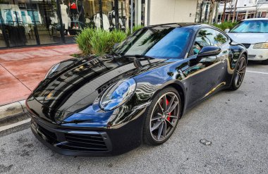 Miami Beach, Florida USA - 8 Haziran 2024 Porsche 911 Carrera 4S Miami Beach 'te siyah. Ocean 'daki lüks araba porshche Miami plajına gidiyor..