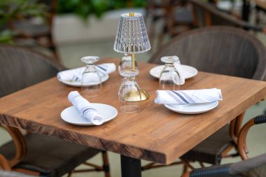 Çanak çömlek ve peçete restorandaki masada. Servis için seramik boş tabaklar. Lüks yemekler servis etmek için yemek takımı. Masa ayarı. Ahşap masada bir takım temiz sofra takımı.