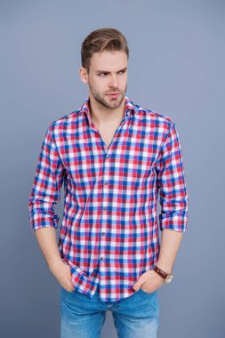 Yakışıklı genç adam. Sıradan gömlekli bir adamın portresi. Gri üzerinde kollarını çapraz tutuyor. Tıraşsız erkek derisi. Erkek güzelliği ve saç stili. Gündelik giyinen milenyum adamı. Moda eklentisi.