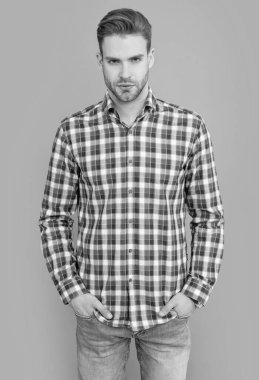 Gri arka planda kareli gömlekli yakışıklı bir adam izole edilmiş. Gündelik tarzda bir adam. Stüdyo fotoğrafı. Beyaz adamın sakalı var..