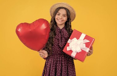 cheerful teen girl with red heart balloon and present box on yellow background. clipart