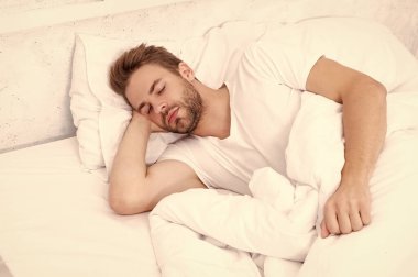 Uykulu adam beyaz yatak odasında uyuyor. Uyuyan genç adam uyuyor. Rahat bir yatakta huzur içinde dinleniyor. Kapalı gözlerle yalan söylemek. Derin erkek uykusu. Geceleri uyuyan bir adam. Huzurlu bir uyku..