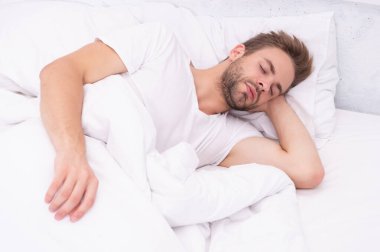 Genç adam uyuyor ya da beyaz yatak odasında evinde uyuyor..