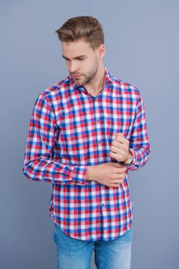 Milenyum erkeğinin gündelik tarzı. Sıradan bir tişörtle genç bir adamın portresi. Tıraşsız adamın şık bir portresi. Gri yolda izole edilmiş bir adam. Kareli gömlek giyen milenyum adamı. Berber dükkanından sonra.