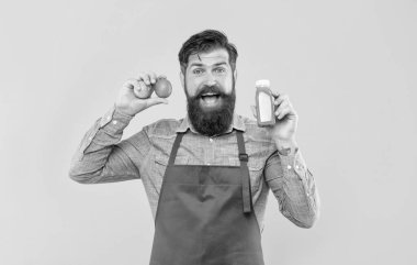 Elinde limon ve meyve suyu şişesi olan mutlu adam sarı arka plan, meyve suyu barmeni.