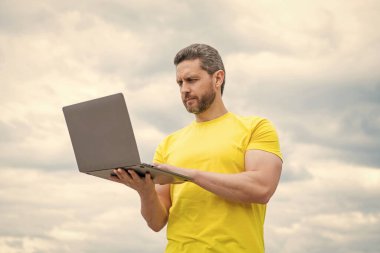 Bilgisayarda çalışan bir adam gökyüzü arka planında. iletişim.