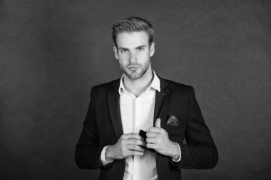 Patron gibi davran. Patron, akıllı telefonu takım elbisesinin cebinden çıkarıyor. Profesyonel bir adam. Ciddi bir yönetmen. İş adamı koyu arkaplan.