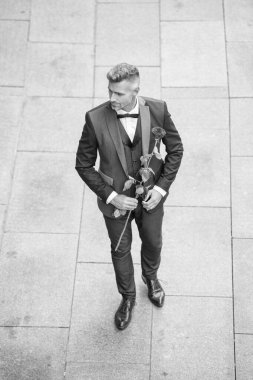 Nişan tarihi. Şık smokinli adam nişanı kutluyor. Nişan için gül hediyeli bir adam.