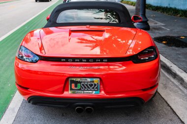 Miami Beach, Florida USA - 9 Haziran 2024: 2018 Porsche 718 Boxter 's orange color at Miami Beach. Ocean 'daki lüks Porsche Miami plajına gidiyor. arka plan