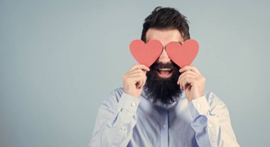Kör aşk. Hippi gözlerini küçük kalplerle kapatıyor. Kırmızı kalp tutan sakallı adam. Kalp şeklinde süslemeleri olan seksi bir adam. Sevgililer günün kutlu olsun. Aşk ve romantizm bayramı, kopyalama alanı.
