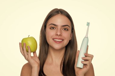 Beyaz tenli dişlek kadın gülüşü. Dişlerini elektrikli diş fırçasıyla fırçalayan bir kadın. Dişlerini fırçalayan bir kız. Beyaz dişler. Diş sağlığı kliniği. Elektrikli diş fırçası. Dönen Sütunlar.