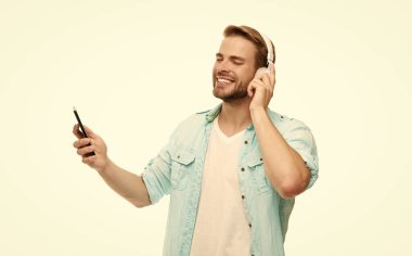 Beyazlar içinde izole edilmiş akıllı telefon uygulaması kullanan adam. Telefonla müzik dinlemek. Müzik yaşam tarzı. Ses çalma listesi. Kulaklıklı adam. Kulaklıklı adam telefonda mp3 çalma listesini seçiyor. Ses kalitesi.