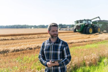 Modern tarımın teknolojisi. Tarlada tabletle çalışan çiftçi. Tablet çekli İspanyol çiftçi. Ekin hasadı. Tarlada tableti olan çiftçi tarımcı adam. Kırsal mahsul.