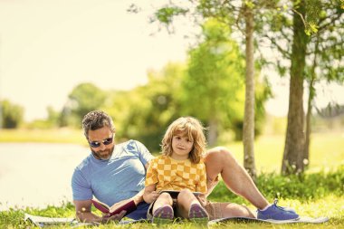 Oğlu ve babası yazın kaynaşıyorlar. Baba ve oğul eğitimi. Baba, oğlunun eğitici yolculuğuna ilham veriyor. Baba oğul parkta rahatlayın. çocukluk okulu eğitimi. Doğa ve öğrenme birleşir.
