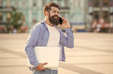Dışarıda cep telefonuyla konuşan mutlu bir adamın portresi. Gülümseyen adam sokakta yürürken cep telefonuyla konuşuyor. Mobil iletişim. Telefon görüşmesi. Cep telefonu çağrısı.