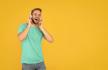 Kablosuz cihaz aksesuarı. Yeni teknoloji. Modern kulaklıklarda şarkı söyleyen mutlu adam. Online eğitim. Okula dönüyorum. Kulaklıklı genç adam. Müzik aşığı. müzik dinle..