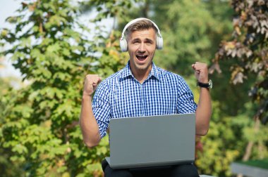 Serbest iş yapma. Dışarıda Webinar dinleyen bir adam. Başarılı bir iş. Çevrimiçi giyin. Kulaklıklı adam. Serbest çalışan adam internette blog yazıyor. Çevrimiçi çalışan serbest çalışan. Serbest çalışmak için dizüstü bilgisayar kullanan adam.