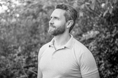 Mavi tişörtlü yakışıklı adamın portresi doğal arka plana bakıyor..