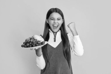 Mutlu çocuk sarı arka planda taze meyve tabağı tutuyor. vitaminler.